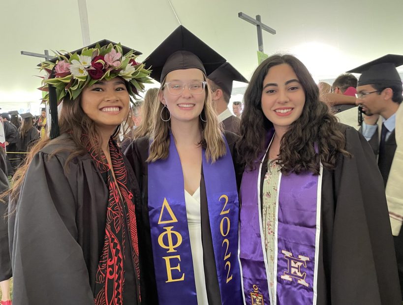 Three students wearing graduation caps and robes.