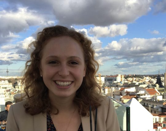 Headshot of white female against city landscape